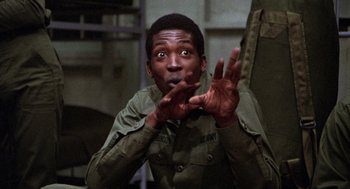 Movie still from “Stripes” (1981), directed by Ivan Reitman – A man in a military uniform holding his hands up in the air; Close Up shot, Low angle