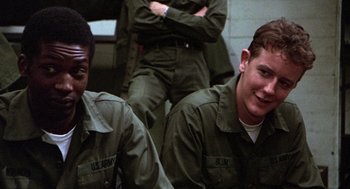 Movie still from “Stripes” (1981), directed by Ivan Reitman – Two young men in army fatigues sitting next to each other; Close Up shot, Over the shoulder angle