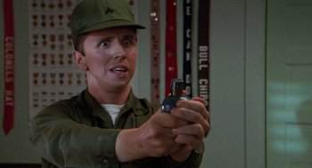 Movie still from “Stripes” (1981), directed by Ivan Reitman – A man holding a cell phone while wearing a hat; Close Up shot, Over the shoulder angle