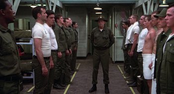 Movie still from “Stripes” (1981), directed by Ivan Reitman – A group of men standing in a room; Wide shot, Low angle