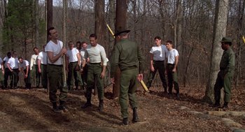 Movie still from “Stripes” (1981), directed by Ivan Reitman – A group of men standing next to each other in the woods; Wide shot, Low angle