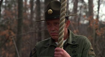 Movie still from “Stripes” (1981), directed by Ivan Reitman – A man in uniform holding a rope in a wooded area; Close Up shot, Low angle