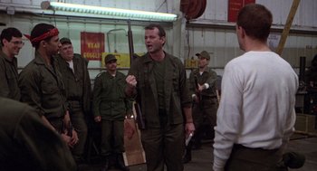 Movie still from “Stripes” (1981), directed by Ivan Reitman – A group of men standing in a room holding guns; Medium shot, Over the shoulder angle