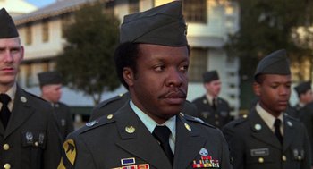 Movie still from “Stripes” (1981), directed by Ivan Reitman – A man in a military uniform is standing in front of other men; Close Up shot, Low angle
