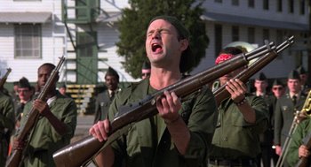 Movie still from “Stripes” (1981), directed by Ivan Reitman – A man holding a rifle in front of a group of people; Medium shot, Low angle