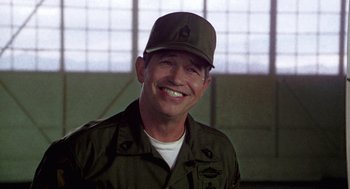 Movie still from “Stripes” (1981), directed by Ivan Reitman – A man wearing a hat and smiling for the camera; Close Up shot, Low angle