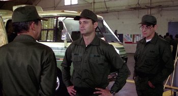 Movie still from “Stripes” (1981), directed by Ivan Reitman – A man in a green uniform standing in front of a truck; Medium shot, Low angle