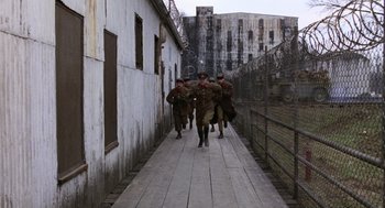 Movie still from “Stripes” (1981), directed by Ivan Reitman – A group of men walking down a wooden walkway; Extreme Wide shot, High angle