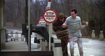Movie still from “Stripes” (1981), directed by Ivan Reitman – Two men are tied to a pole by a stop sign; Wide shot, High angle