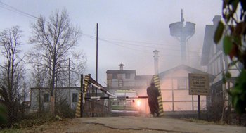 Movie still from “Stripes” (1981), directed by Ivan Reitman – A person standing in front of an open gate; Extreme Wide shot, High angle