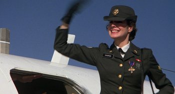 Movie still from “Stripes” (1981), directed by Ivan Reitman – A woman in a military uniform waving at the crowd; Medium shot, Low angle