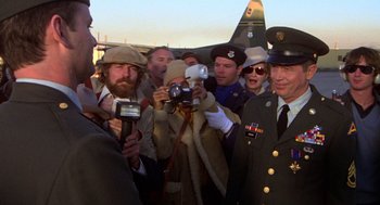 Movie still from “Stripes” (1981), directed by Ivan Reitman – A group of people standing next to each other holding cameras; Medium shot, Over the shoulder angle