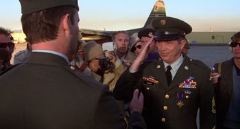 Movie still from “Stripes” (1981), directed by Ivan Reitman – A man in a military uniform saluting another man; Medium shot, Over the shoulder angle