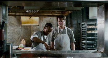 Movie still from “Super” (2010), directed by James Gunn – A man and a woman working in a restaurant kitchen; Medium shot, Low angle