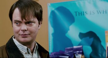 Movie still from “Super” (2010), directed by James Gunn – A person with a book in front of him; Close Up shot, Over the shoulder angle