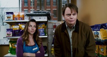 Movie still from “Super” (2010), directed by James Gunn – A man and a woman standing next to each other in a store; Medium shot, Over the shoulder angle