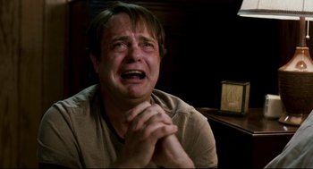 Movie still from “Super” (2010), directed by James Gunn – A man sitting in front of an alarm clock crying; Close Up shot, High angle