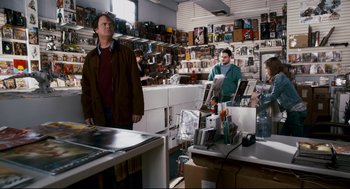 Movie still from “Super” (2010), directed by James Gunn – A man standing next to another man in a store; Medium shot, Over the shoulder angle