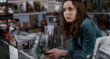 Movie still from “Super” (2010), directed by James Gunn – A woman in a denim jacket looking at a camera; Close Up shot, Over the shoulder angle