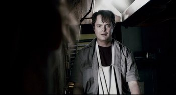 Movie still from “Super” (2010), directed by James Gunn – A man wearing an apron standing next to a wall; Close Up shot, Low angle