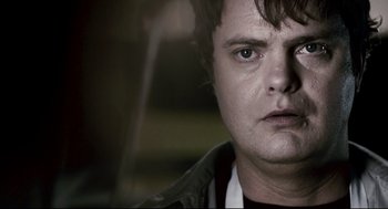 Movie still from “Super” (2010), directed by James Gunn – A man's face in a dark room; Close Up shot, Over the shoulder angle
