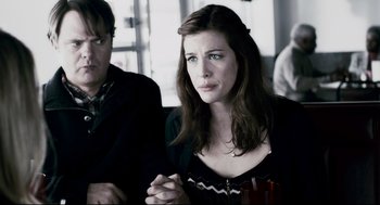Movie still from “Super” (2010), directed by James Gunn – A woman sitting next to a man in a room; Medium shot, Over the shoulder angle