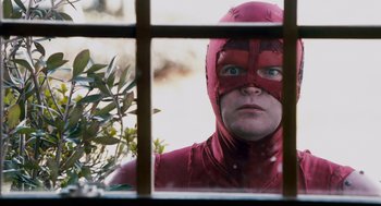 Movie still from “Super” (2010), directed by James Gunn – A man in a red costume looking out of a window; Close Up shot, Low angle