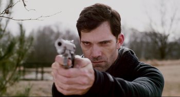 Movie still from “Super” (2010), directed by James Gunn – A man holding a gun in his hand; Close Up shot, Over the shoulder angle