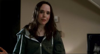 Movie still from “Super” (2010), directed by James Gunn – A woman with long brown hair wearing a gray jacket; Close Up shot, Over the shoulder angle