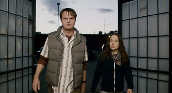 Movie still from “Super” (2010), directed by James Gunn – A man and a woman standing next to each other on a sidewalk; Medium shot, Low angle