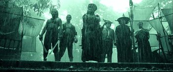 Movie still from “Ong Bak 3” (2010), directed by Tony Jaa – A group of people standing next to each other in the rain; Wide shot, Low angle