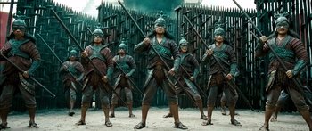 Movie still from “Ong Bak 3” (2010), directed by Tony Jaa – A group of men standing next to each other holding arrows; Wide shot, Low angle