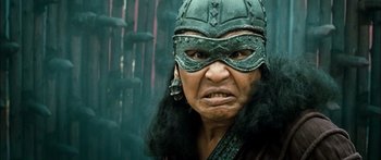 Movie still from “Ong Bak 3” (2010), directed by Tony Jaa – An old woman wearing a viking helmet and a mask; Close Up shot, Low angle
