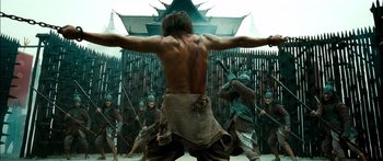 Movie still from “Ong Bak 3” (2010), directed by Tony Jaa – A group of people in costume in front of a building; Wide shot, Low angle