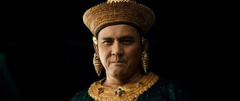 Movie still from “Ong Bak 3” (2010), directed by Tony Jaa – A man wearing a gold crown and a green shirt; Close Up shot, Low angle