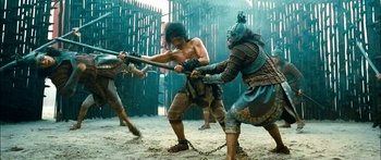 Movie still from “Ong Bak 3” (2010), directed by Tony Jaa – A group of men in costume fighting in the sand; Wide shot, Low angle