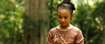 Movie still from “Ong Bak 3” (2010), directed by Tony Jaa – A young girl holding a snail in her hands; Close Up shot, Over the shoulder angle