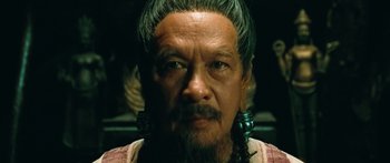 Movie still from “Ong Bak 3” (2010), directed by Tony Jaa – An older man with long hair and green eyes; Close Up shot, Low angle