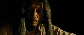 Movie still from “Ong Bak 3” (2010), directed by Tony Jaa – A man with long black hair and a white shirt; Close Up shot, High angle