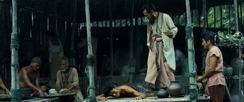 Movie still from “Ong Bak 3” (2010), directed by Tony Jaa – A man is laying on the ground next to another man; Wide shot, High angle
