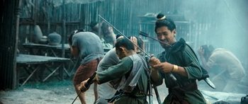 Movie still from “Ong Bak 3” (2010), directed by Tony Jaa – A group of men are fighting in the rain; Medium shot, Over the shoulder angle