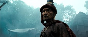 Movie still from “Ong Bak 3” (2010), directed by Tony Jaa – A man wearing a hat and a long scarf; Close Up shot, Over the shoulder angle