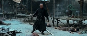 Movie still from “Ong Bak 3” (2010), directed by Tony Jaa – A man in a black robe is holding a sword; Medium shot, High angle