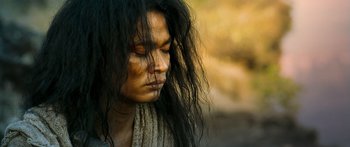 Movie still from “Ong Bak 3” (2010), directed by Tony Jaa – A man with long black hair is looking to his left; Close Up shot, High angle
