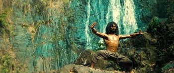 Movie still from “Ong Bak 3” (2010), directed by Tony Jaa – A shirtless man standing in front of a body of water; Medium shot, Low angle