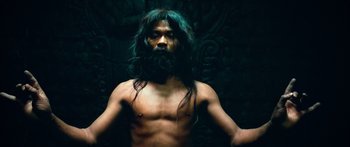 Movie still from “Ong Bak 3” (2010), directed by Tony Jaa – A man with long green hair and a beard; Medium shot, Overhead angle