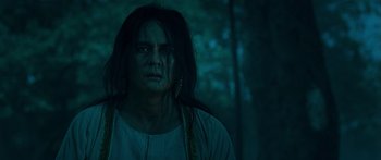 Movie still from “Ong Bak 3” (2010), directed by Tony Jaa – A man with long black hair is standing in the woods; Close Up shot, Low angle