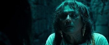 Movie still from “Ong Bak 3” (2010), directed by Tony Jaa – A man with long hair is staring at the camera; Close Up shot, Low angle