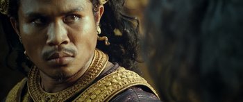 Movie still from “Ong Bak 3” (2010), directed by Tony Jaa – A person wearing a gold necklace; Close Up shot, Over the shoulder angle