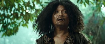 Movie still from “Ong Bak 3” (2010), directed by Tony Jaa – A man with long black hair is looking up at the sky; Close Up shot, Over the shoulder angle